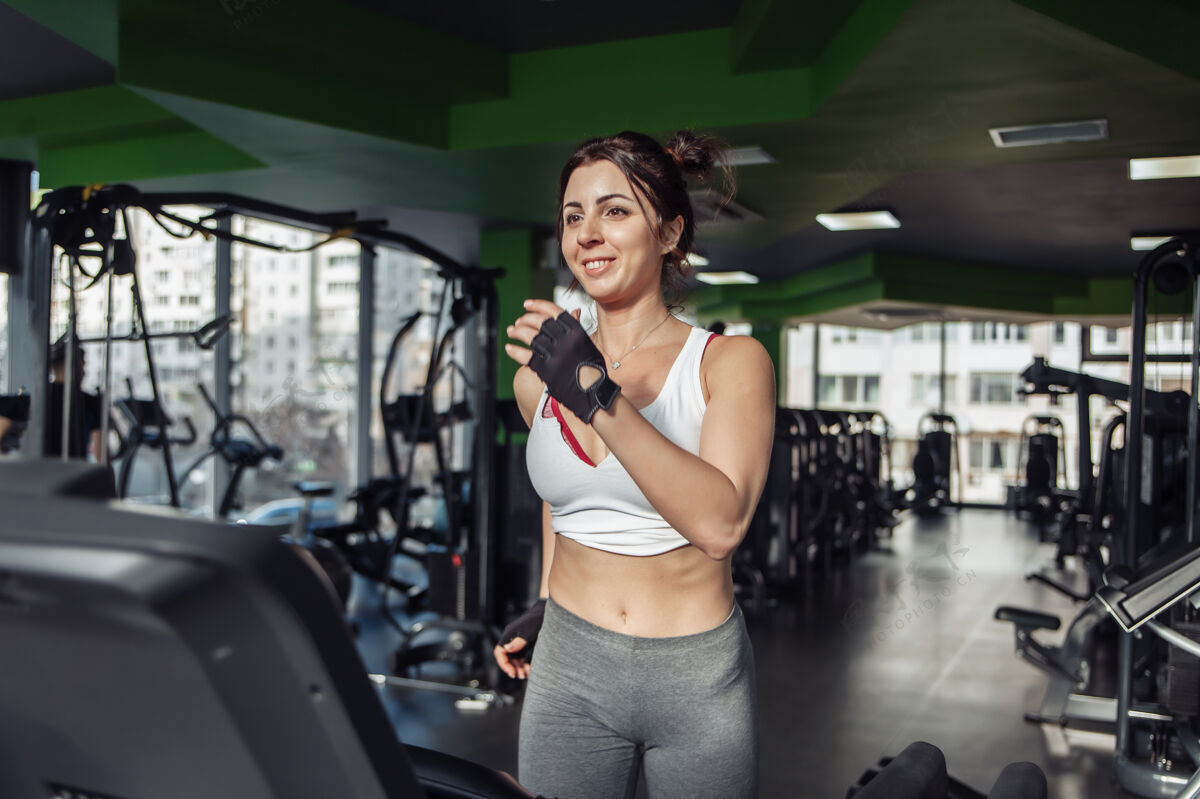 跑道在健身房的跑步机上穿着运动服的快乐苗条的女人活动强壮训练