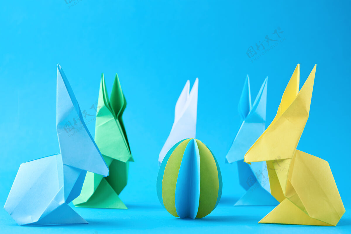 手工纸折纸把兔子和彩蛋放在蓝色的墙上复活节庆祝概念工艺鸡蛋创造