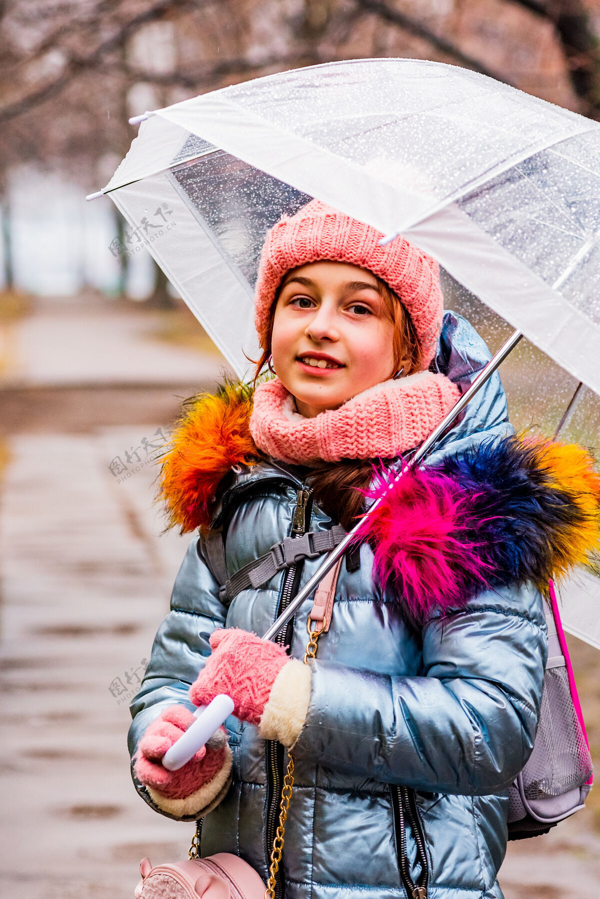 雨金发碧眼的女孩穿着夹克带着透明的雨伞在外面的雨中御寒外套寒冷户外
