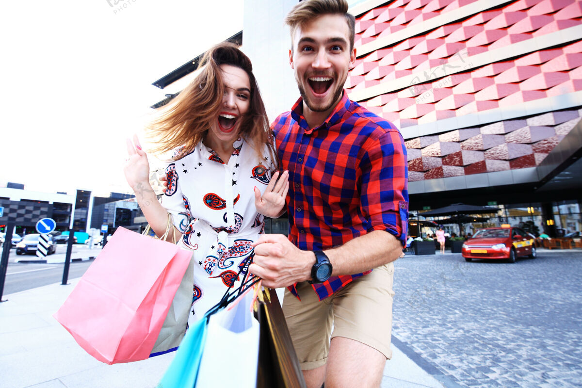 关系带着购物袋的年轻幸福的一对欢乐零售城市
