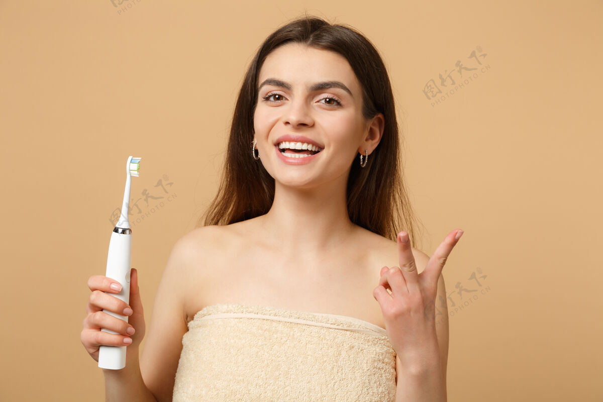 女人特写黑发半裸完美皮肤的女人 裸妆握刷隔离在米色粉彩墙上牙科防护药物