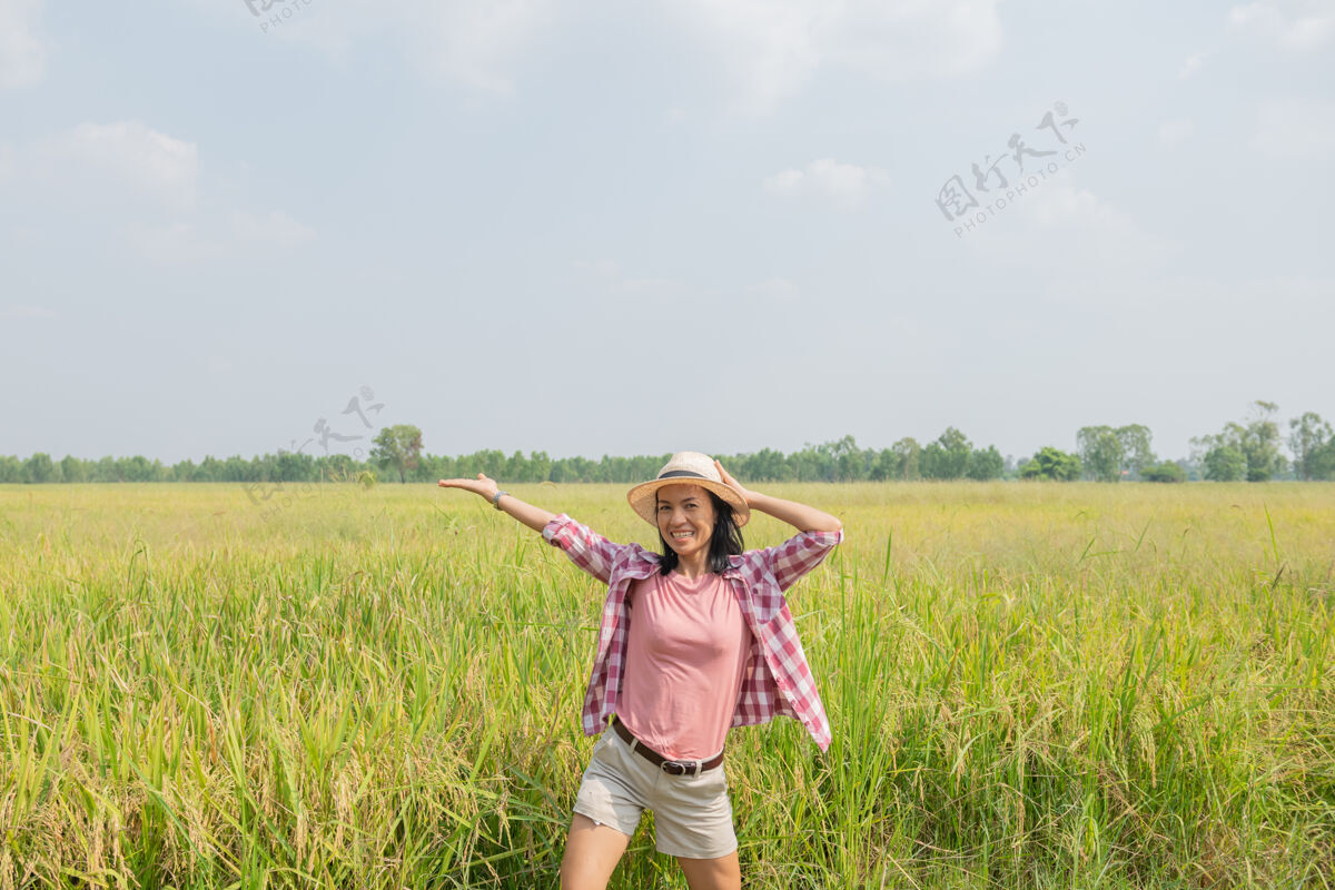 模特行走在泰国稻田里的年轻女子去清洁地球的地方旅行 发现大自然的美丽戴着帽子站着的年轻女子旅行者大米女士食物