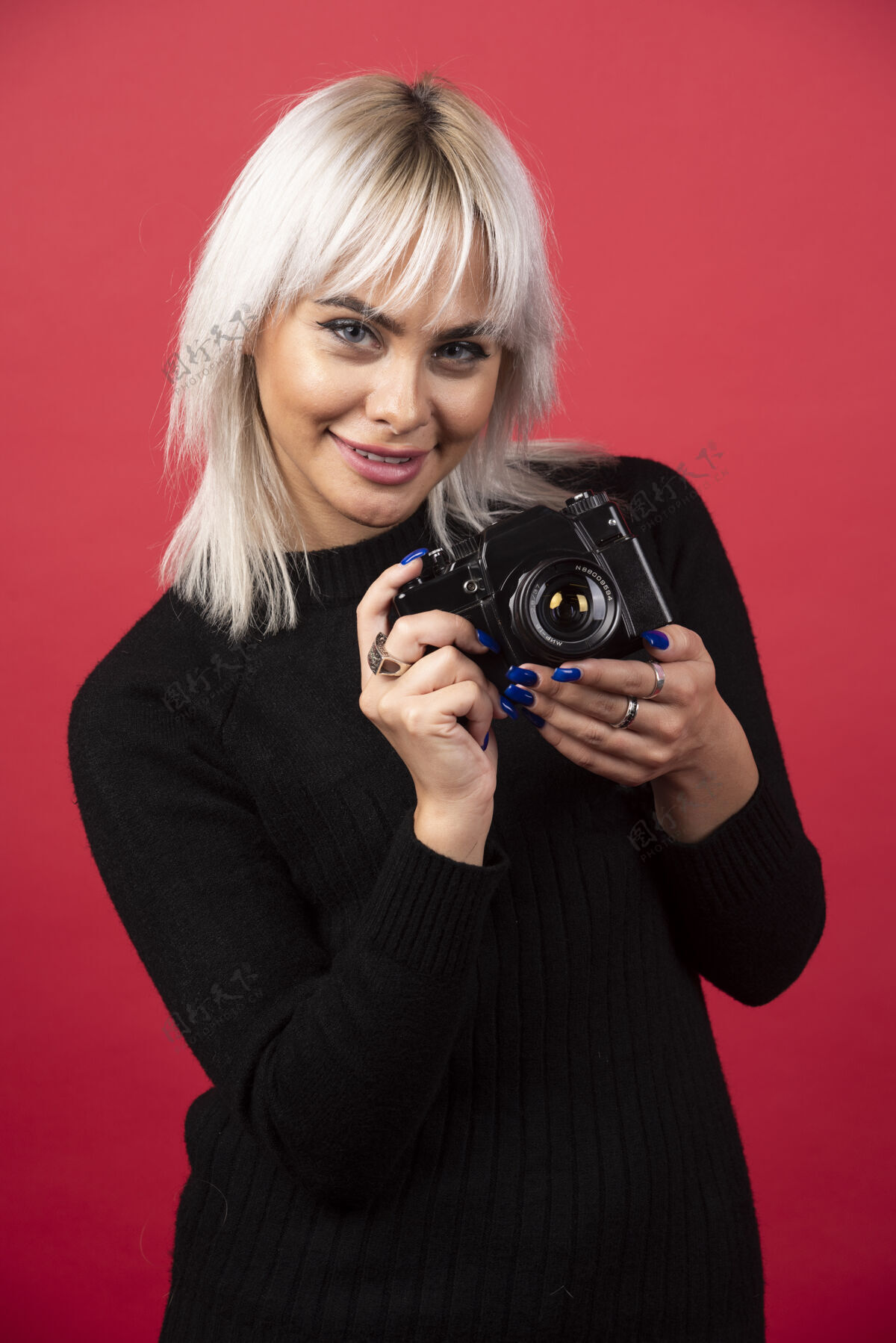 女性化美丽的年轻女子手持相机站在红色背景下高品质的照片女孩摄影师女士