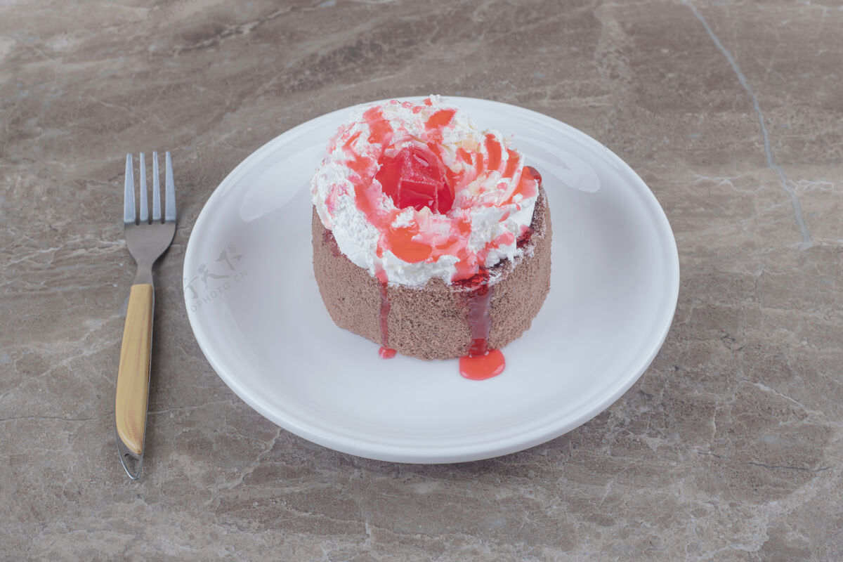 烘焙一个小蛋糕 上面放着奶油和草莓糖浆 放在大理石盘子上糖浆口感蛋糕