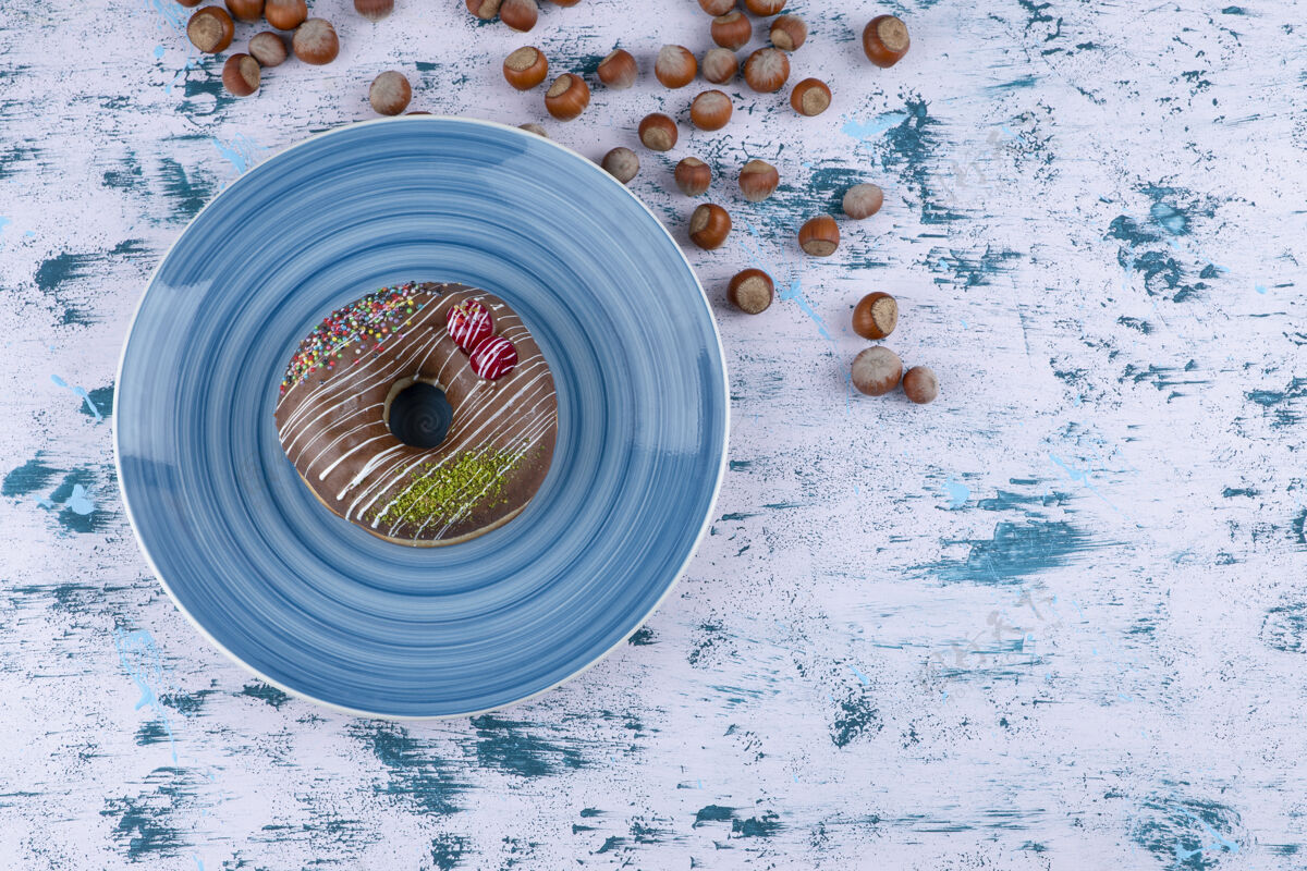 浆果蓝色盘子 白色表面有巧克力甜甜圈和带壳榛子蛋糕贝壳面包房