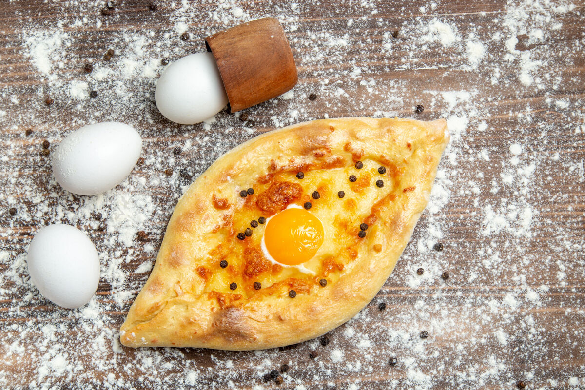 面包俯视图烤面包与熟鸡蛋和面粉上的棕色书桌面团鸡蛋面包包早餐酱汁顶部鸡蛋