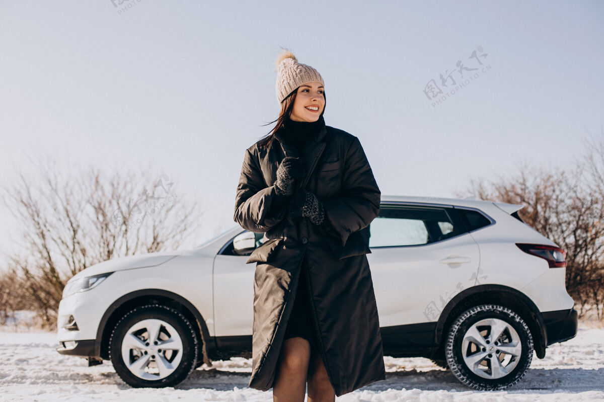 站着拿着咖啡的女人站在冬天田野里的车旁风景冬天度假
