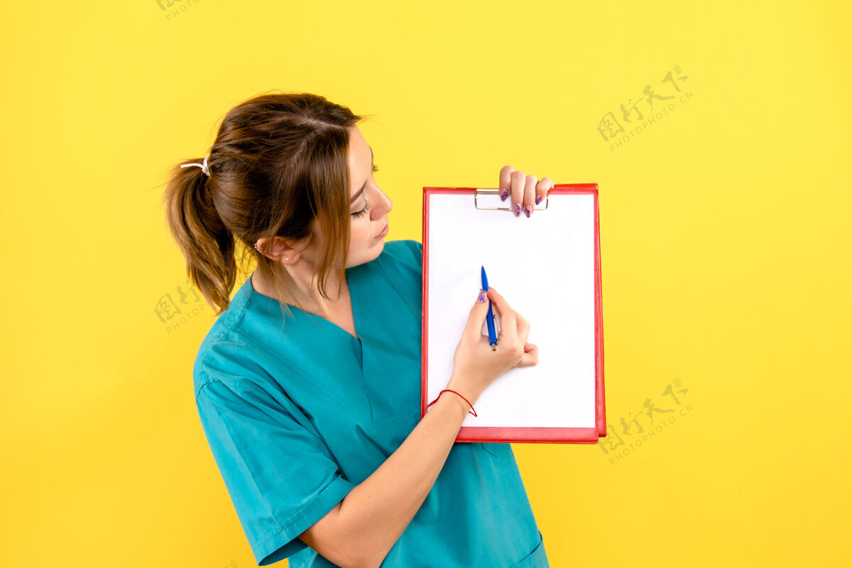 快乐黄色墙上拿着钢笔和文件的女兽医的正面图笔人微笑