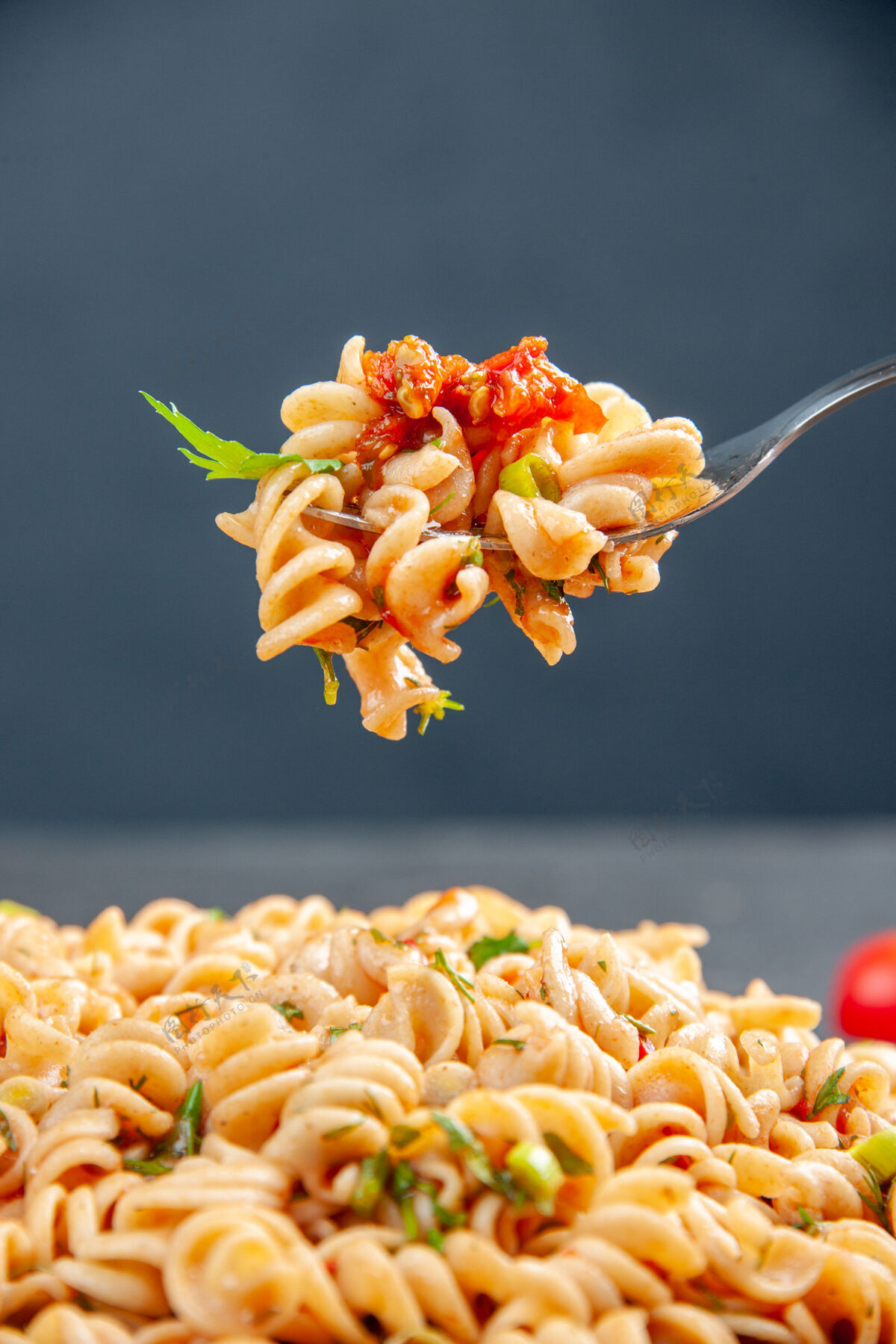 意大利面前视图罗蒂尼面食在盘子和叉子上黑暗的孤立表面花花瓣盘子