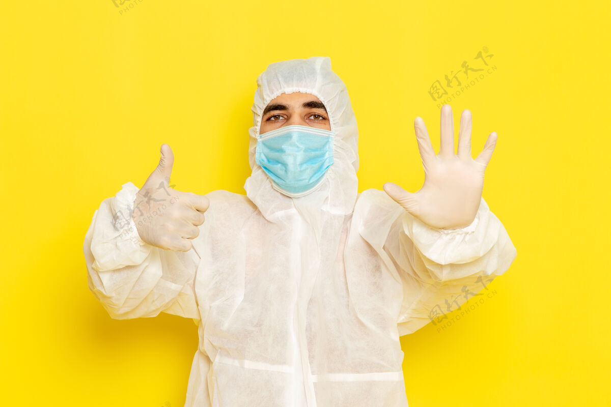 正面身穿特殊防护服 戴着面罩的男性科学工作者的正面图 手掌放在淡黄色的墙上男性服装危险