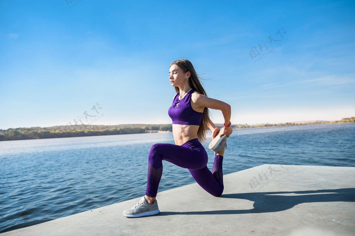 早晨运动型的年轻女子白天在湖边做健身操休闲运动员体重