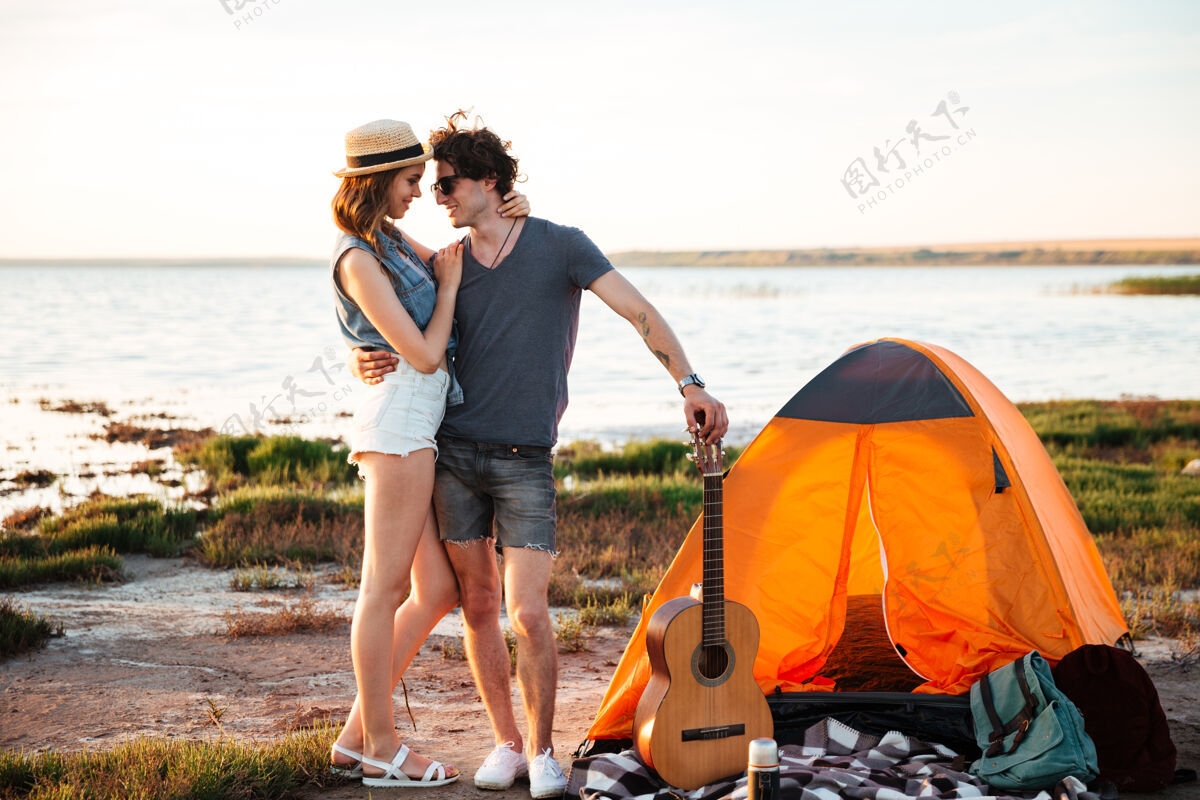 人在露营帐篷前拥抱的快乐的年轻迷人的夫妇的肖像夏天女性户外