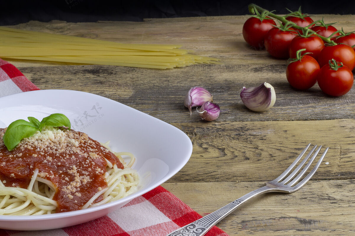 房子木桌上放着素食意大利面 背景是西红柿 大蒜和意大利面木材烹饪食物