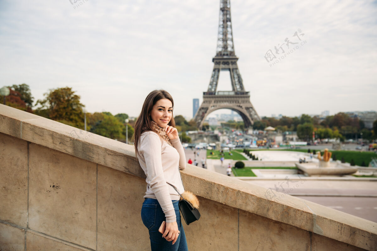 女人在埃菲尔铁塔的背景下 美丽的女孩向摄影师摆姿势秋天女孩人巴黎人