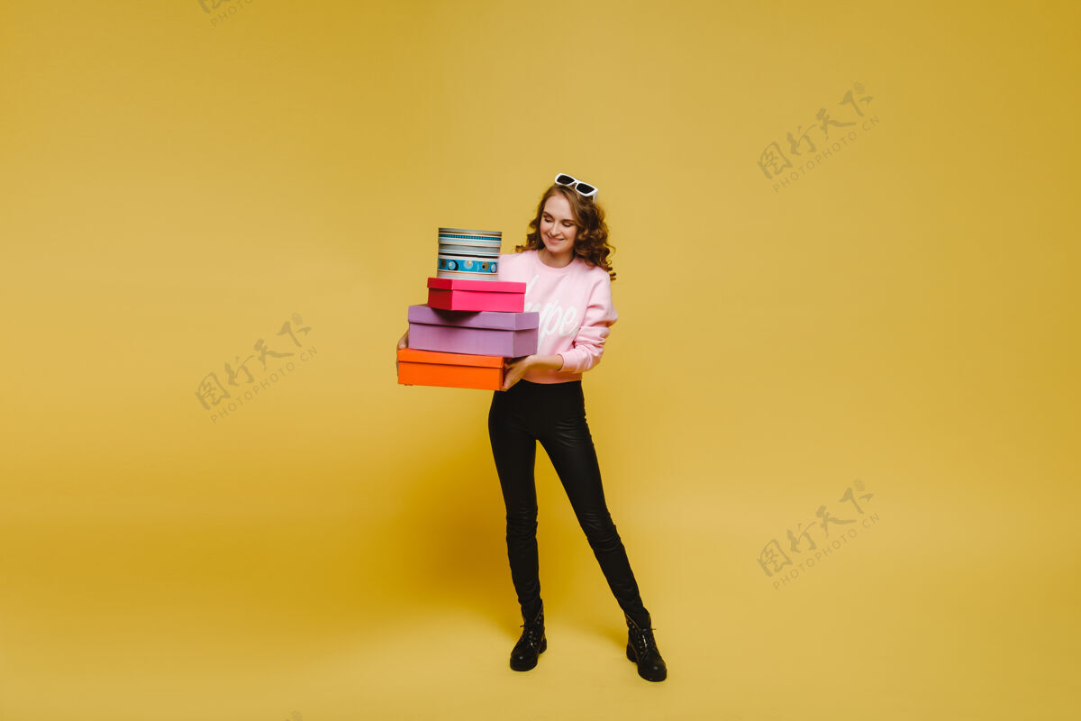 买家一个快乐的年轻女子 购物后带着五颜六色的纸盒子 在橙色的工作室背景上与世隔绝购物狂市场携带