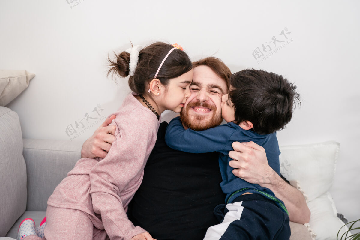 团结父亲和两个孩子在家里的沙发上拥抱和玩耍的特写照片跨国家庭真实的生活 团结 多样性 家庭舒适真实的真实的人欢呼