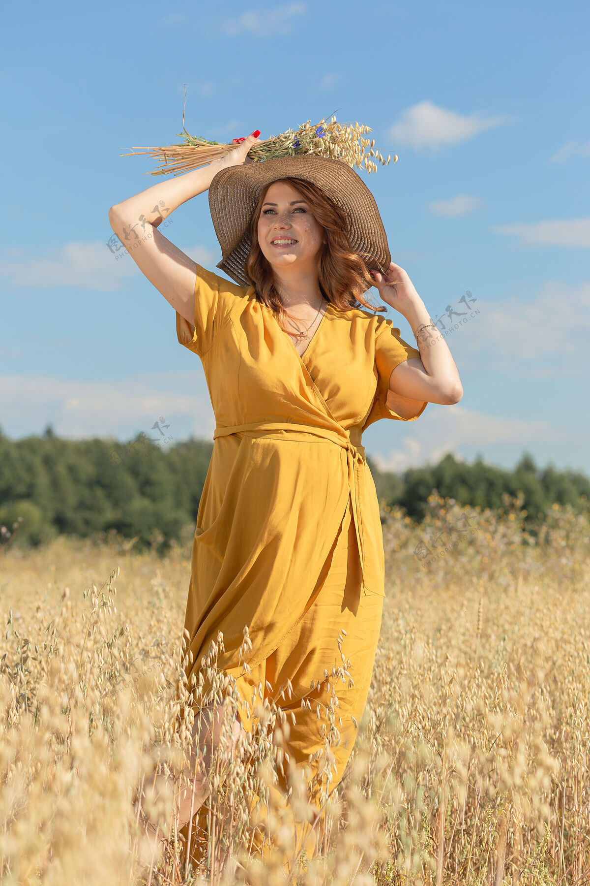 人在一个阳光明媚的夏日 一位年轻漂亮的孕妇穿着黄色的裙子 戴着黄色的帽子 走过一片麦田肚子天空自然