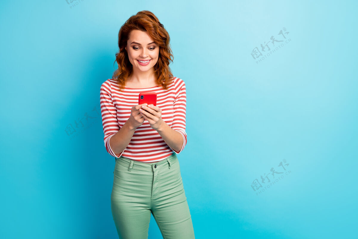 Swoosh正面开朗女性肖像使用智能手机阅读社交媒体新闻信息穿着时尚的套头衫隔离蓝色信息帖子在线