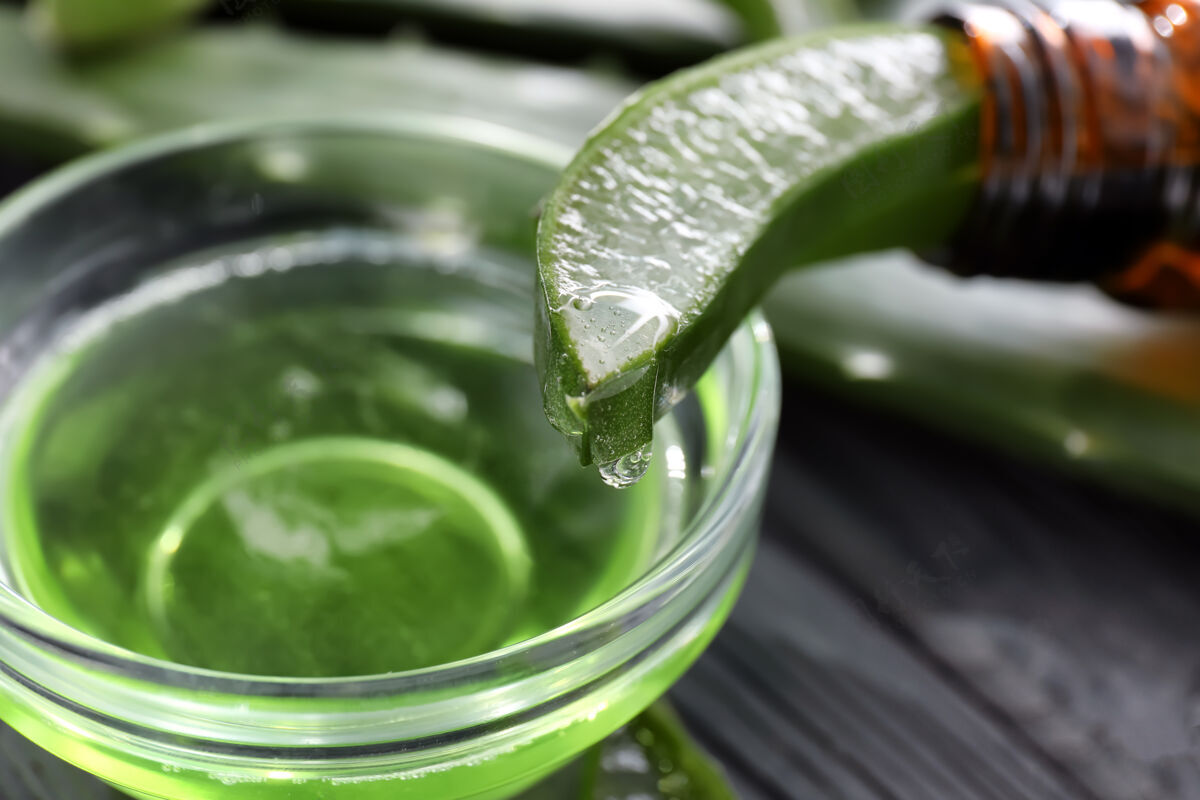 桌子芦荟汁从绿叶滴入碗中 特写芦荟滴剂药物