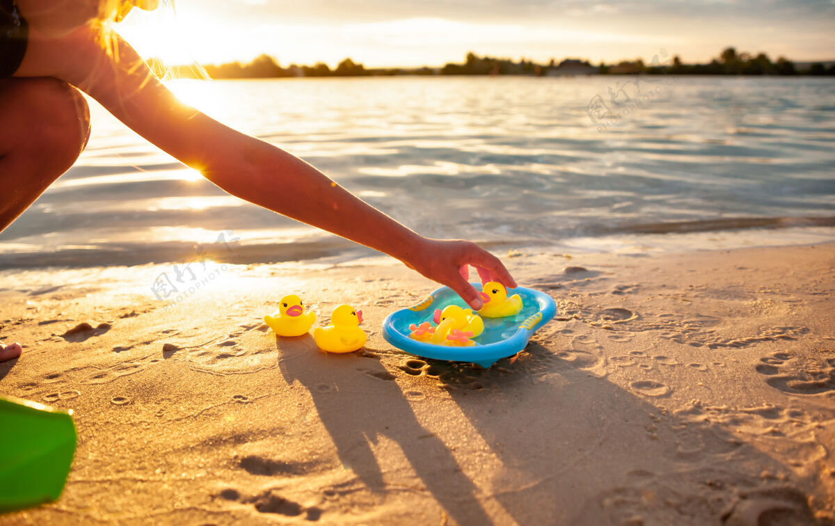 快乐在蓝色的小水池里 坐在海边 一个认不出来的白人小孩的手在玩橡皮黄鸭子旅游鸭子自然