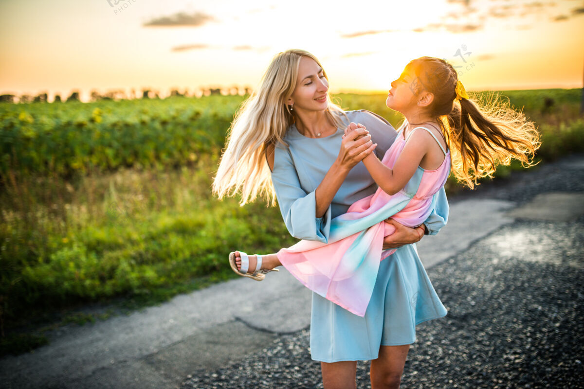 玩耍美丽快乐的年轻妈妈把她有趣的小女儿抱在怀里美丽欢呼白天