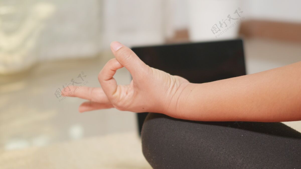 健康在家练习瑜伽的紧身裤 坐在瑜伽垫上的莲花姿势女性年轻姿势