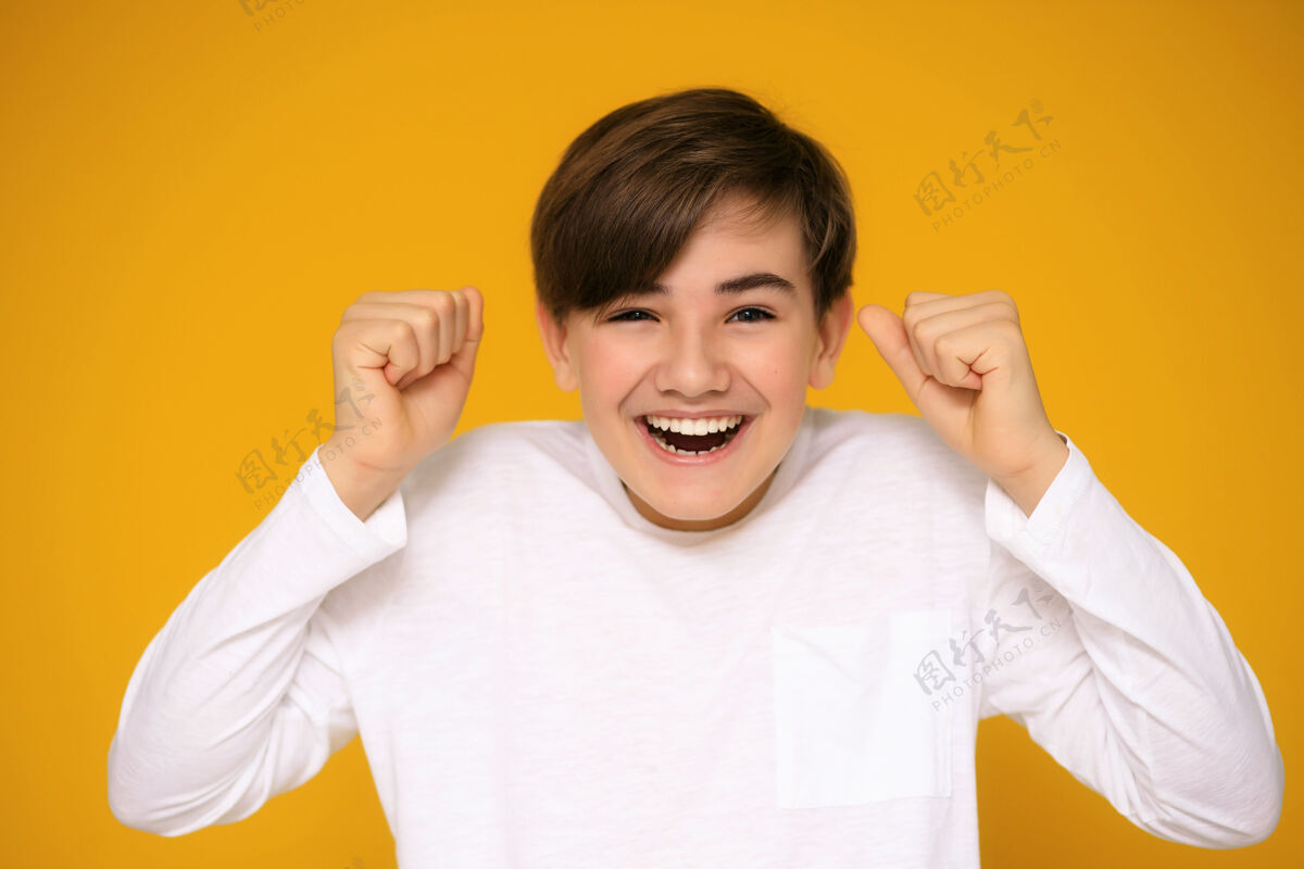 孩子黄色背景上一个12-13岁的英俊少年的画像乐趣手生活方式
