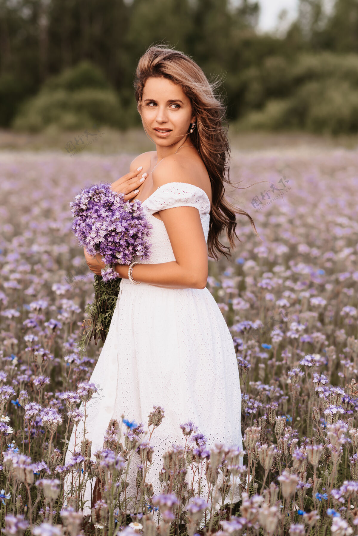 田野夏天 在大自然的田野里 一个穿着白裙子 开着一束紫色花朵的女孩户外生活方式年轻