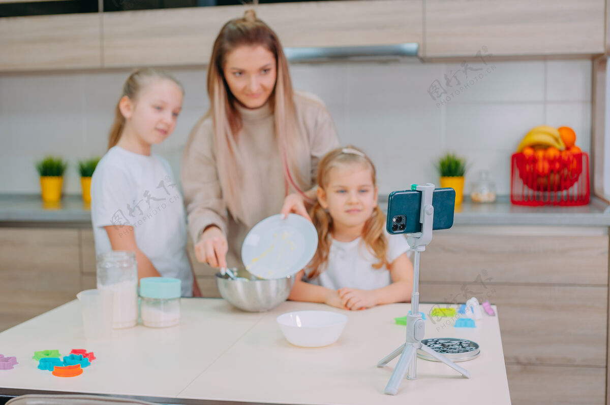债券妈妈在厨房教女儿们做面团家庭鸡蛋盘子