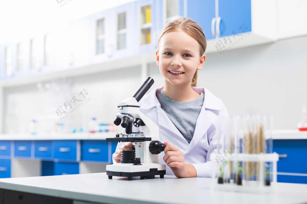 科学好的我是同性恋迷人的积极的女孩在实验室摆姿势 同时看着相机和调整显微镜意识学习者尼斯