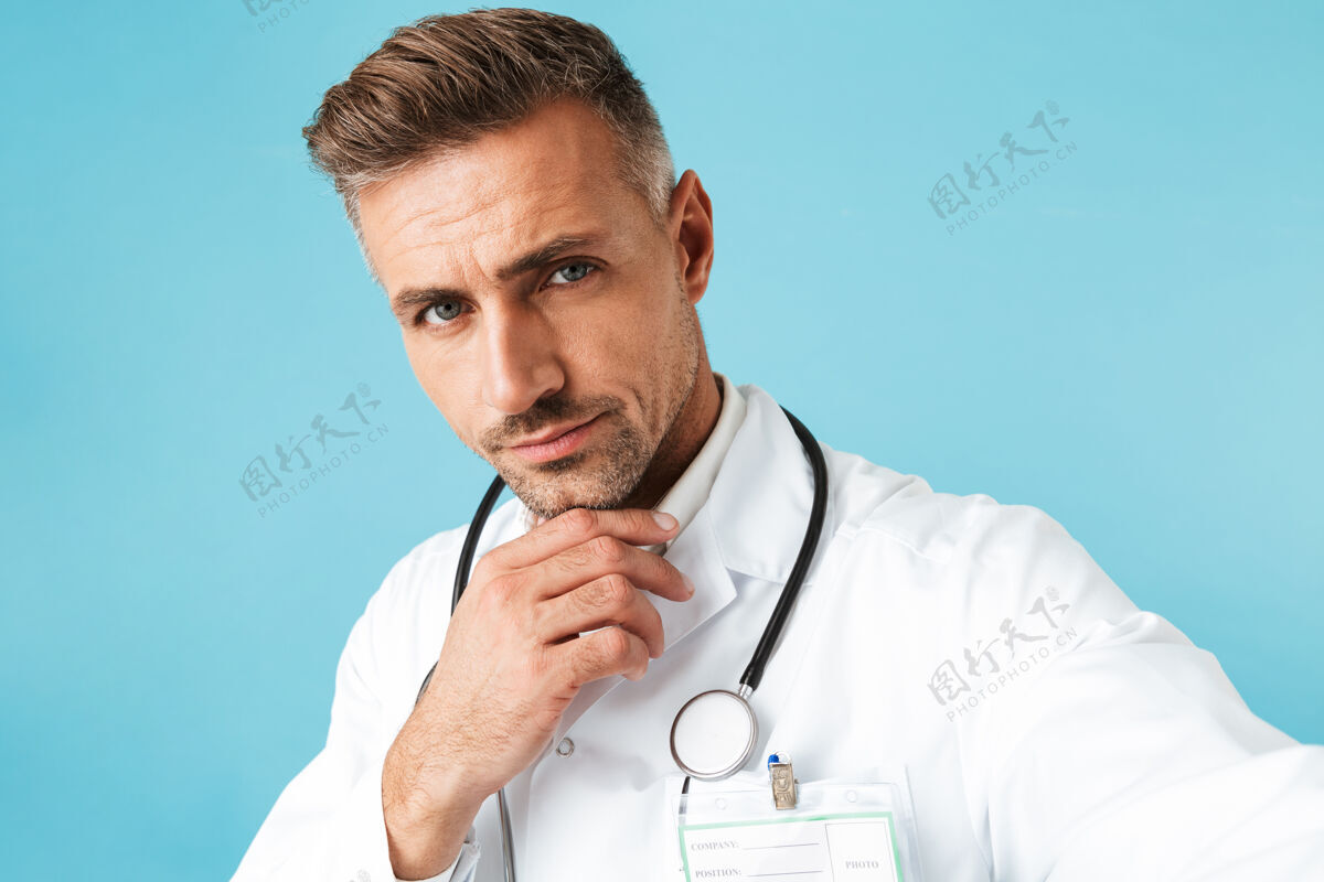 东西一张带听诊器的成熟医生独自站在蓝色墙壁上自拍的照片听诊器从业者肖像