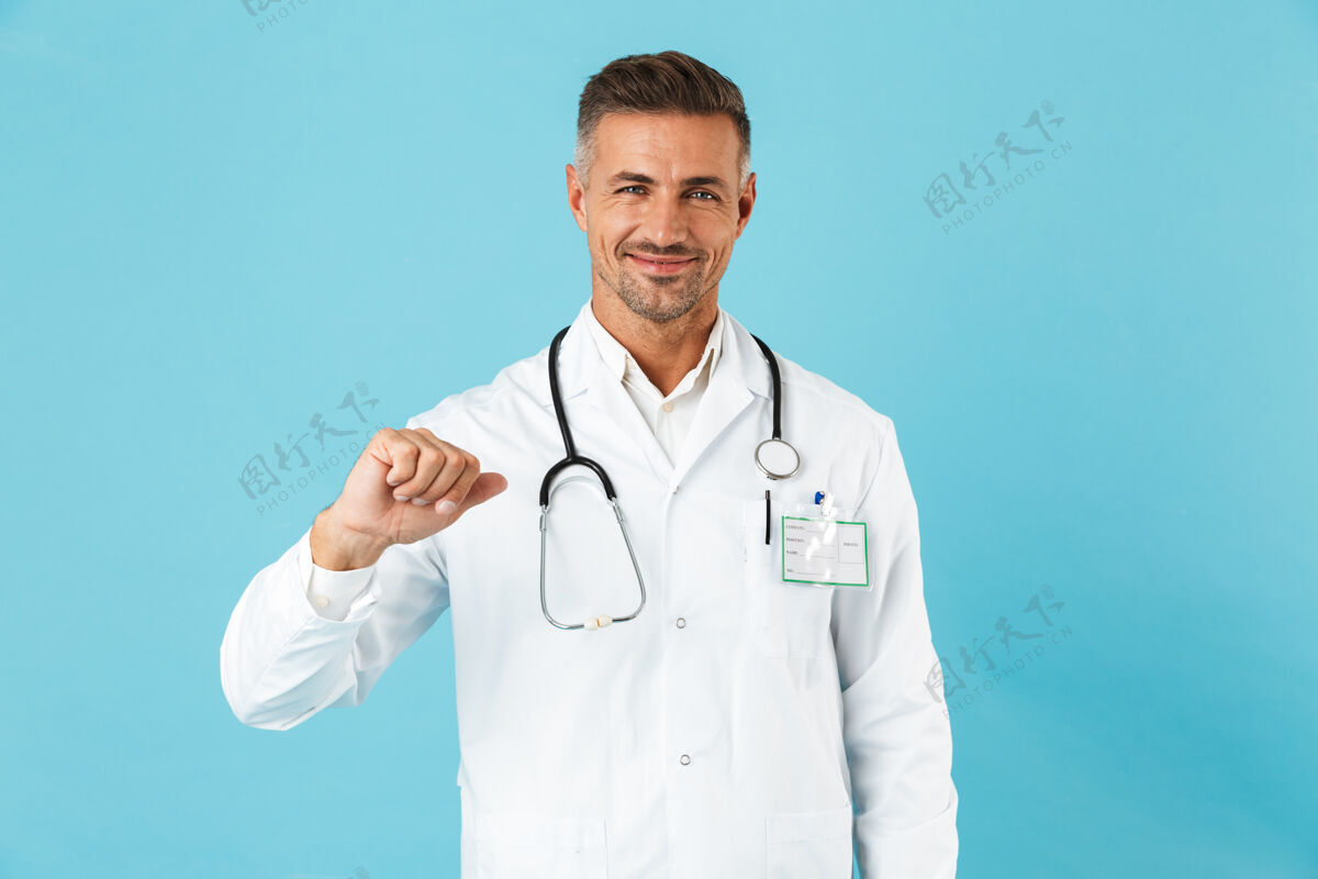 男人自信的男人医生穿着制服孤立地站在蓝色的墙上 指着自己指点医生秀