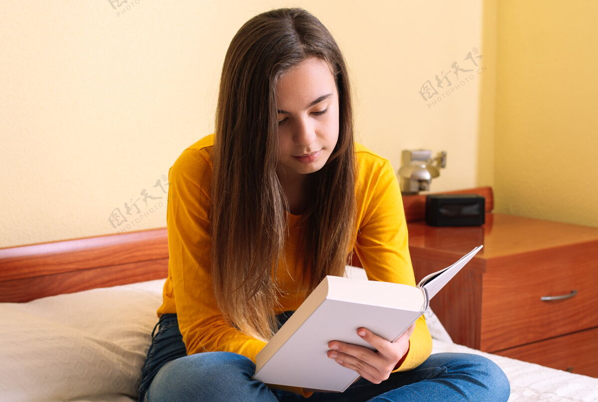 睫毛坐在床上看书的年轻女子放松看民族