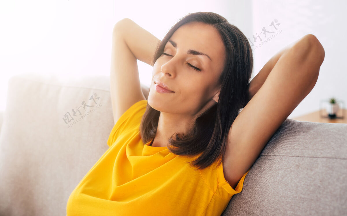 自由美丽 冷静 自信的棕发女人假期在家里的沙发上休息年轻健康快乐