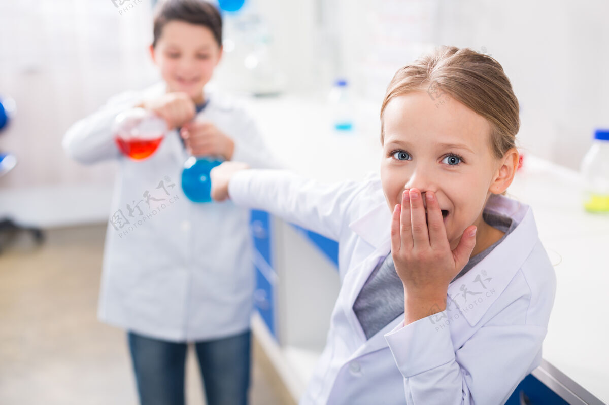 特写太有趣了很好的积极兴奋的女孩看着你 捂着嘴和她的朋友做实验生物显微镜研究
