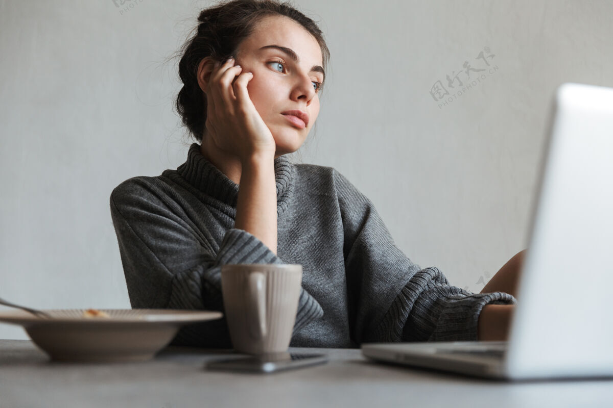 女人坐在厨房里用笔记本电脑吃健康早餐的年轻漂亮女人积极舒适处方