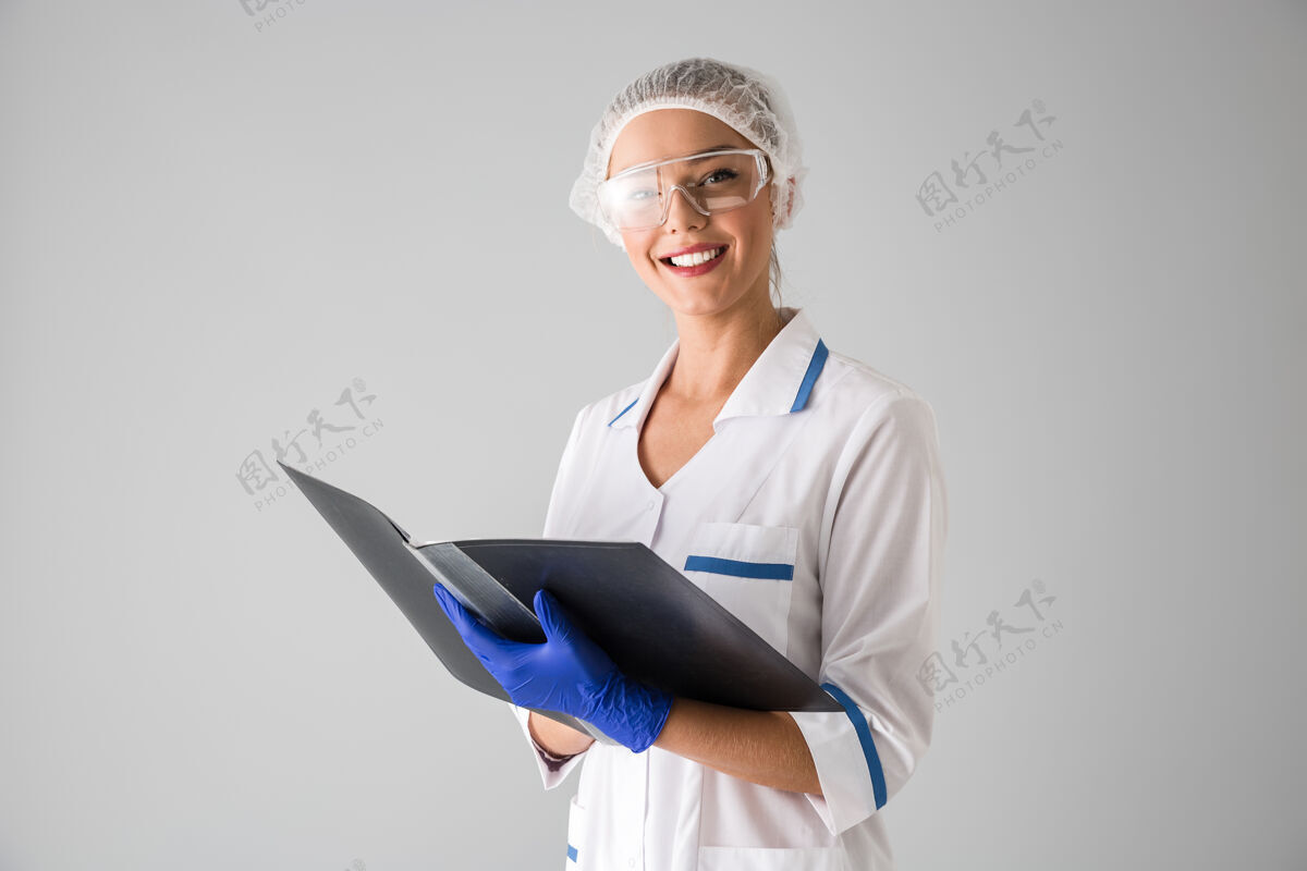 实践一个年轻漂亮的女美容师医生的形象被隔离在灰色的墙上拿着文件夹肖像儿科医生外科医生