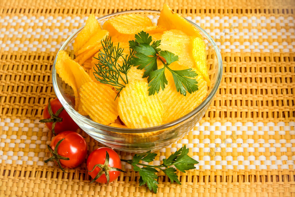 切片在一个透明的碗里放上天然的脆薯片 里面有莳萝叶 欧芹叶和三个樱桃番茄吃卡路里垃圾食品