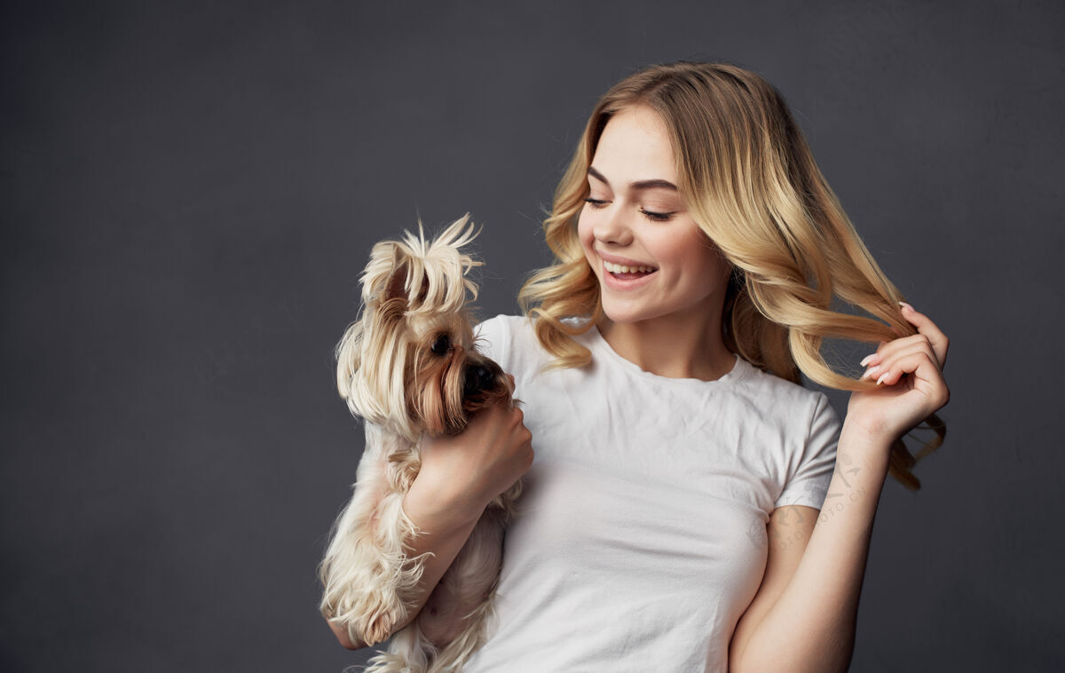 年轻人一个穿着白色t恤的快乐漂亮女人手里拿着一只小狗和宠物成人金发通讯