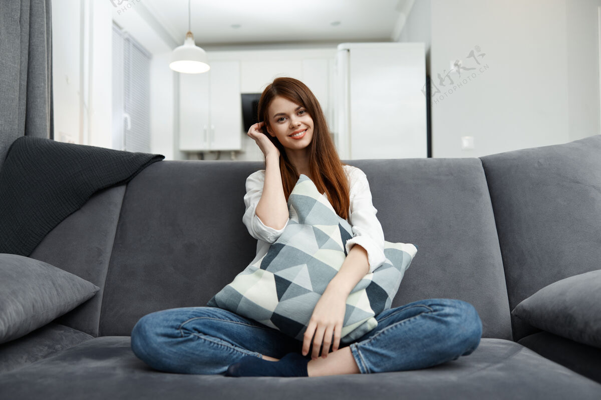 休闲微笑的女人在家里 手里拿着枕头舒适的沙发公寓肖像成人豪华