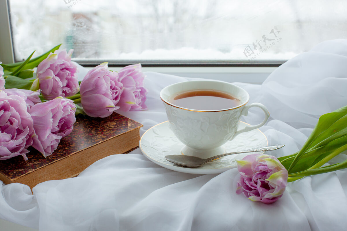 咖啡一杯茶一本旧书一束郁金香在窗户上自然甜书桌