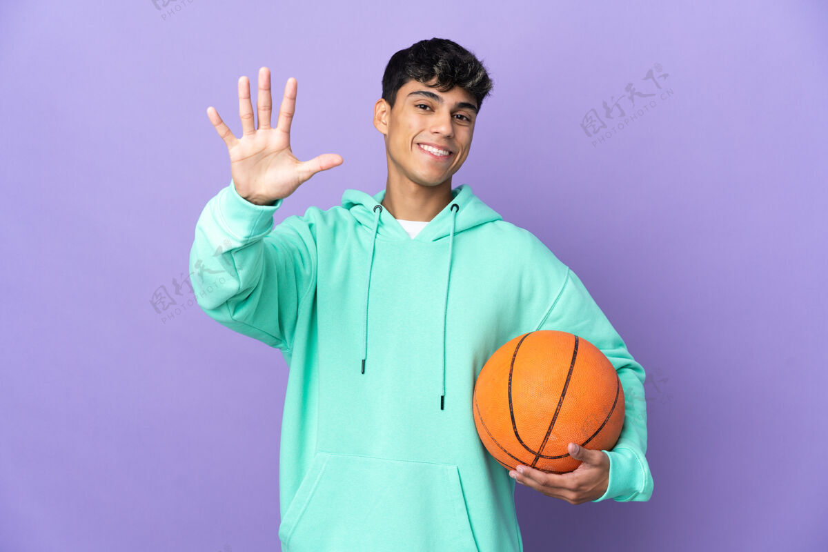 手指年轻人在孤立的紫色墙壁上打篮球 用手指数到五人五点