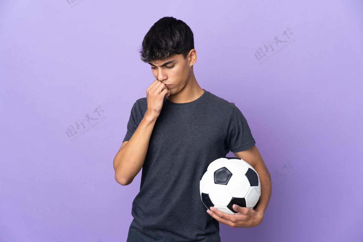 年轻一个年轻的足球运动员越过隔离的紫墙 心中充满疑惑训练思考知道