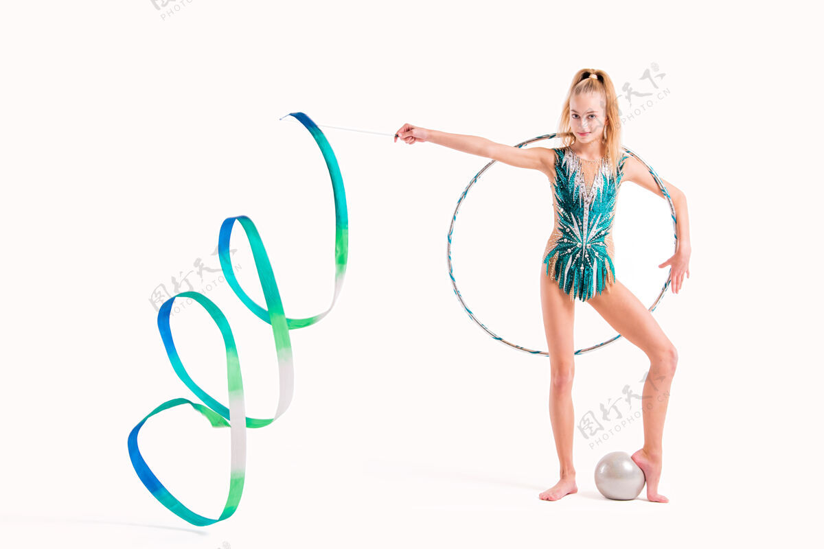运动一位身着翡翠泳装的职业体操女运动员微笑着 在白色泳衣上系着丝带 篮球圈和球金发翡翠平衡
