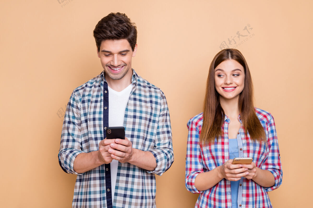 微笑他\/她漂亮迷人开朗开朗的夫妇穿着格子衬衫的特写肖像使用现代媒体营销5g应用程序隔离在米色粉彩背景上女人手机女朋友