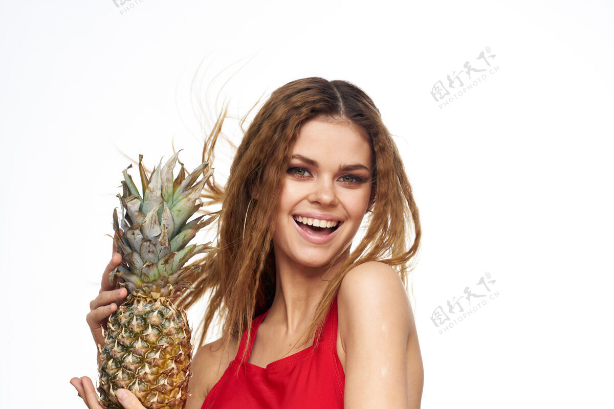 性感手拿菠萝的女人波浪形头发红色t恤水果夏日轻墙微笑女人酒精