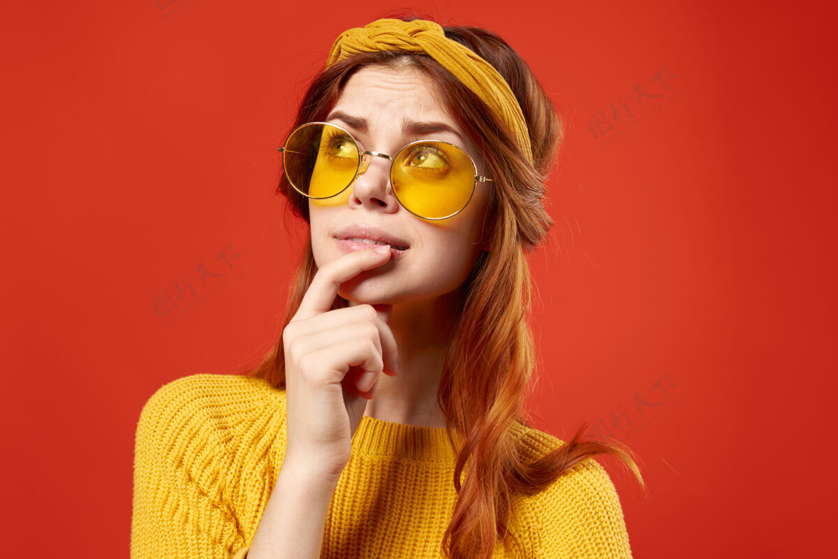 性感情绪化的女人戴着眼镜黄色毛衣休闲装嬉皮红墙女士时髦女人