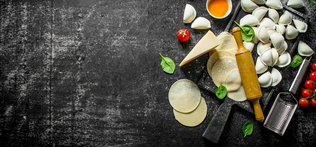 传统黑木桌上有菠菜叶 帕尔玛干酪和蛋黄的生饺子膳食帕尔马干酪肉
