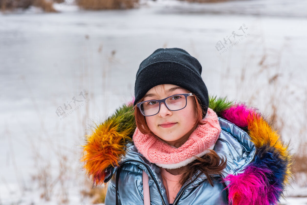 肖像冬天的女孩衣服女孩10年老年人蓝色的夹克女孩戴着黑帽子散步河流青少年女孩