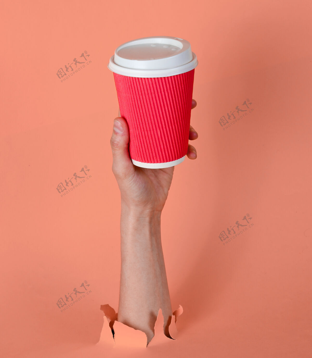 最小女性的手拿着纸咖啡杯穿过撕破的粉红色纸简约概念创意饮料手